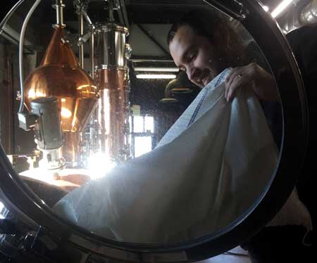 James pouring malt into a mash tun at a distillery